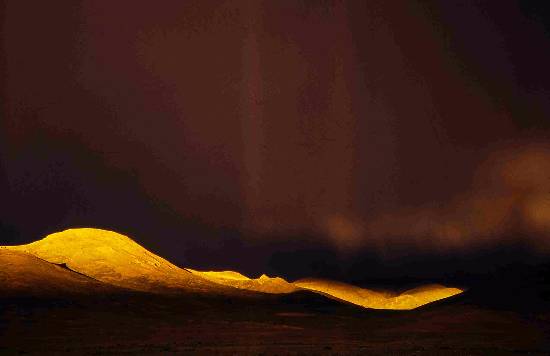 Photograph by Ashok Dilwali - Last rays of sun break through thick clouds on a hill in Tibet