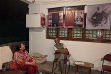 Dr Pratibha Patwardhan in conversation with artist Kishor Randiwe with panels relating to Leo Tolstoy in the background at Indiaart Gallery