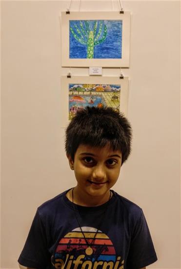 Aarav Kanekar with his painting in the background at Khula Aasmaan exhibition